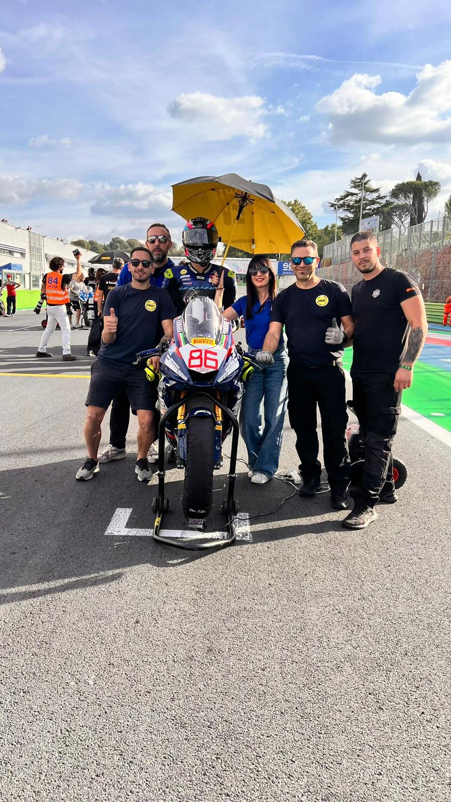 EMC2 al fianco del pilota e della moto numero 86 sulla griglia di partenza